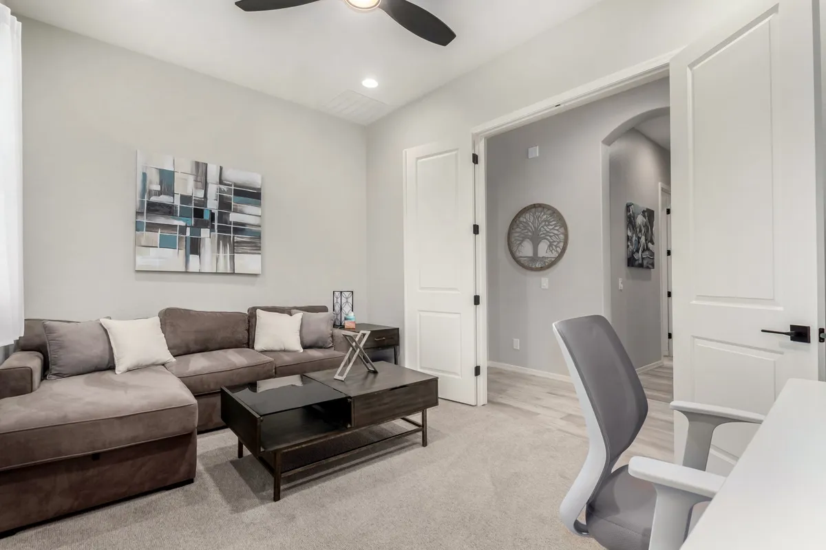 This image displays a comfortable, contemporary room with a sectional sofa, a coffee table, and artistic wall decor. The ambiance is inviting and stylish, suitable for both productive work-from-home days and moments of relaxation or inspiration. The layout suggests a space that is not just for work, but also for enjoying downtime or creative activities.