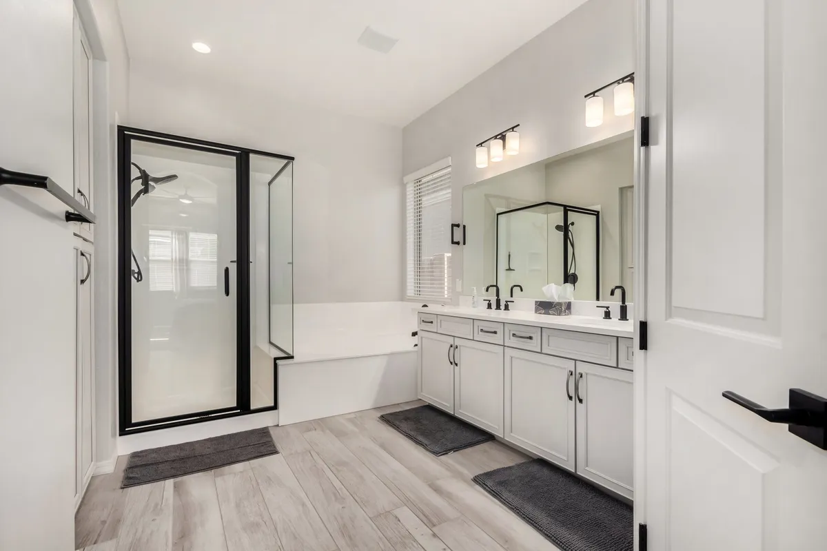 A luxurious, modern bathroom featuring a double vanity with mirrors, a glass shower enclosure, and a freestanding bathtub. The room is bathed in soft, natural light, creating a rejuvenating atmosphere perfect for self-care.